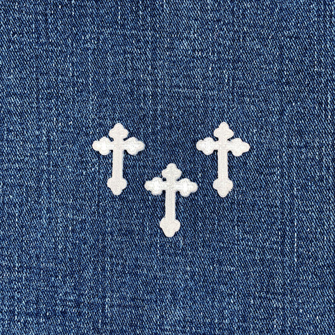 3 White cross-shaped patches on a blue denim background