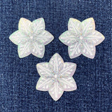 Three star-shaped iridescent snowflake patches on a denim background