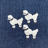 Three white poodle dog patches on a denim background