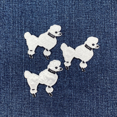 Three white poodle dog patches on a blue denim background