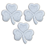 Three small white embroidered shamrock patches on a white background