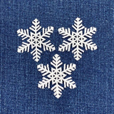 Three white snowflakes on a blue denim background