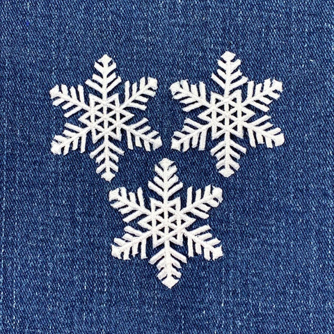 Three white snowflakes on a blue denim background