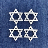 Four white embroidered Star of David patches arranged in a 2x2 grid on a textured blue denim fabric background.