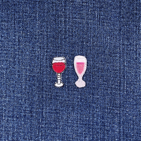 Two embroidered wine glass patches on a denim background