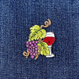 Embroidered patch of a glass of red wine with grapes on denim fabric