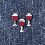 Three embroidered patches depicting glasses of red wine, with an iron-on backing on a denim background