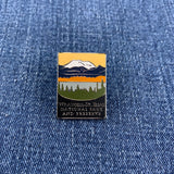Pin with mountain and forest Wrangell St Elias National Park design on a blue denim background