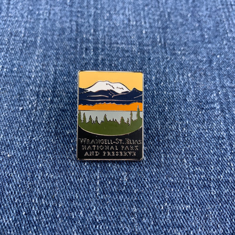 Pin with mountain and forest Wrangell St Elias National Park design on a blue denim background
