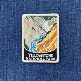 An embroidered rectangular patch for Yellowstone National Park with white text reading 'YELLOWSTONE NATIONAL PARK' and displayed on a denim background