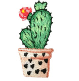 A patch depicting a green cactus with a pink flower in a brown pot with black heart patterns.