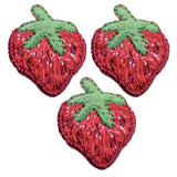 Three red strawberry patches with green leaves 