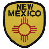 A shield-shaped embroidered patch with 'NEW MEXICO' written at the top. The patch features a red sun symbol on a yellow background with a black border.