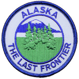 A round embroidered patch featuring the landscape of Alaska with mountains and trees, and the text 'Alaska The Last Frontier'.