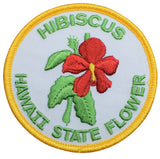 A round embroidered patch featuring a red Hibiscus flower with green leaves on a white background, with text that reads 'HIBISCUS HAWAII STATE FLOWER'.