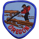 A shield-shaped embroidered patch with a blue border and a depiction of a lumberjack standing on a log with the word 'OREGON' below.