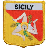A shield-shaped embroidered patch with 'SICILY' written at the top. The design includes a winged figure holding wheat, set against a red and yellow background with a yellow border.