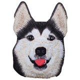 An embroidered patch depicting a smiling Husky Malamute dog with a black and white coat and a red tongue, designed for ironing onto fabric.