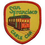A shield-shaped embroidered patch featuring a San Francisco cable car on a yellow background, with the words "San Francisco CABLE CAR" embroidered in green.