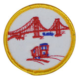 A round embroidered patch featuring the Golden Gate Bridge and a cable car on a white background with a yellow border.