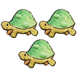Three embroidered patches depicting green and yellow turtles, designed to be ironed onto fabric.