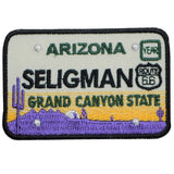 A patch with the design of an Arizona Route 66 license plate, featuring Grand Canyon motifs in purple, yellow, and green colors.