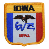 A shield-shaped patch with a blue and white design featuring an eagle, and the text 'IOWA' in bold. The patch has a yellow border and is designed for iron-on application.