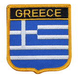 A shield-shaped embroidered patch with the text 'GREECE' and the flag of Greece's stripes in blue and white.