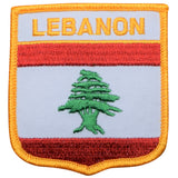 A shield-shaped patch with a red and white vertical stripe pattern and a green cedar tree emblem in the center. The text 'LEBANON' is written at the top in bold letters.
