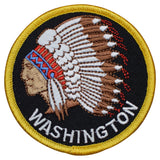 A circular patch with a Native American headdress design, predominantly featuring a face with a headdress, in colors white, red, black, and yellow, with the word 'WASHINGTON' across the bottom.