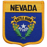 A shield-shaped embroidered patch with blue background, yellow border, featuring the text 'NEVADA' at the top, a floral design with the text 'BATTLE Born NEVADA' and a star emblem in the center.