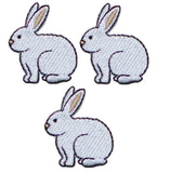 Three embroidered patches depicting white rabbits in a sitting position, arranged in a triangular formation against a white background.
