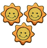 Three sun-shaped applique patches with a smiling face, in yellow, orange, and black colors, designed to be ironed onto fabric.