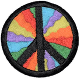 A round patch with a peace sign design, featuring a rainbow color spectrum and a black border, intended to be ironed onto fabric.