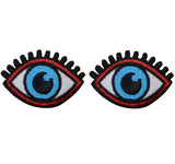two patches depicting a pair of blue eyes with black eyelashes and an iron on backing, arranged side by side on a white background