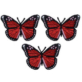 Three identical embroidered patches of a butterfly with bright red wings, black borders, and small white details, arranged on a white background.