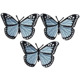 Three light blue butterfly applique patches with black outlines, designed to be ironed onto fabric.