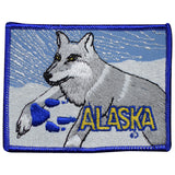 A patch featuring an embroidered image of a husky with 'Alaska' text below it, predominantly grey and white with a blue border.