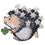 Embroidered hedgehog patch holding a four-leaf clover, featuring white daisies tucked into its dark grey and black quills.