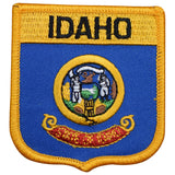 A shield-shaped embroidered patch featuring the Idaho state seal with the name 'IDAHO' above it, bordered by a gold-colored trim.