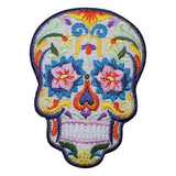 A colorful embroidered patch in the shape of a sugar skull, designed as a Dia de los Muertos or Halloween badge.