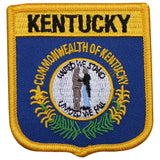 A shield-shaped embroidered patch with blue, gold, and green colors, featuring text and an emblem, indicating it is a representation of Kentucky.