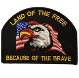 An embroidered patch featuring an eagle with a flag and the text 'LAND OF THE FREE BECAUSE OF THE BRAVE'.