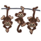 A patch with three embroidered monkeys hanging from a branch.