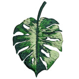 A embroidered applique patch depicting a green Monstera leaf with a tropical pattern.