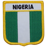 A shield-shaped embroidered patch with vertical green and white stripes and the text 'NIGERIA' across the top. The patch has a yellow border and is designed for iron-on application.