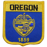 A shield-shaped embroidered patch with blue background and yellow text and design elements, featuring the word 'OREGON' and the year '1859' at the bottom.