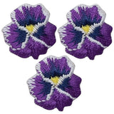 Three embroidered patches depicting pansy flowers with purple petals and a yellow center