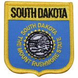 A shield-shaped patch with blue background and yellow trim. The patch has text and an emblem that represents South Dakota.