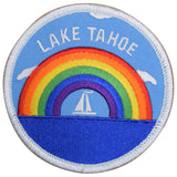A round embroidered patch featuring a rainbow with a sailboat in the center, and the text 'LAKE TAHOE' across the top. The patch has a blue background resembling water and is framed with a white stitched border.